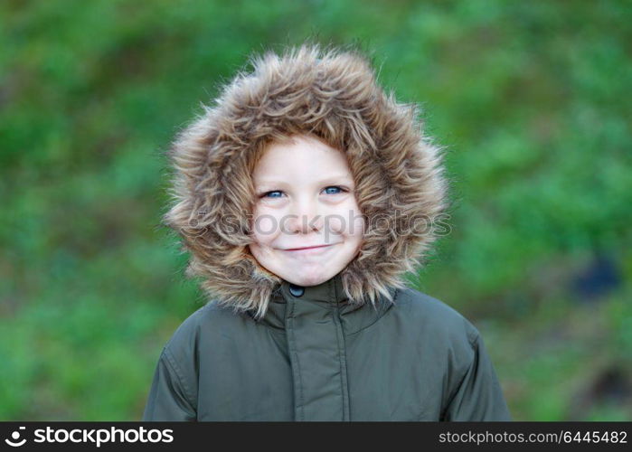 Small child in the park with a warm coat and a green grass of background