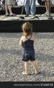 Small child watching live outdoor concert.