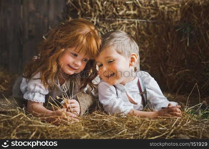 Small children play among the hay.. Red-haired girl and boy playing with rabbit in the hay 6119.