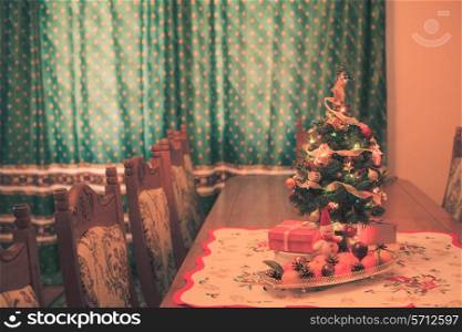 Small Christmas tree with decorations, gifts and citrus on the table