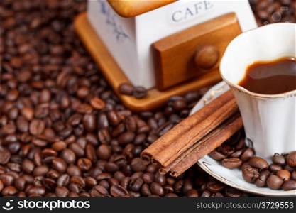 small cup of coffee and roasted coffee beans with retro manual mill, cinnamon close up