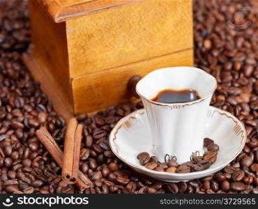 small cup of coffee and roasted coffee beans with retro wood manual mill, cinnamon close up
