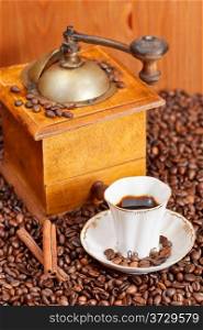 small cup of coffee and roasted coffee beans with retro wooden manual grinder, cinnamon