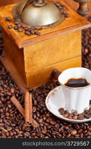 small cup of coffee and roasted coffee beans with retro wooden manual mill, cinnamon