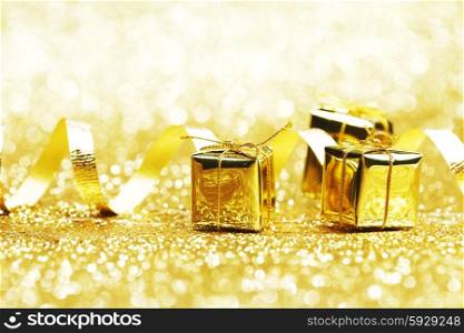 Small decorative golden presents on glitter background