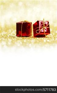 Small decorative red presents on golden glitter background