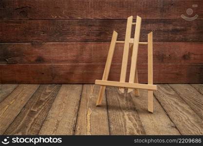 small empty easel against rustic, weathered, wooden background