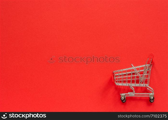 Small empty shopping trolley cart on red background. Concept sale. Top view Copy space.. Small empty shopping trolley cart on red background. Concept sale. Top view Copy space