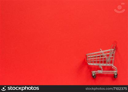 Small empty shopping trolley cart on red background. Concept sale. Top view Copy space.. Small empty shopping trolley cart on red background. Concept sale. Top view Copy space