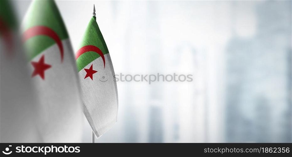 Small flags of Algeria on a blurry background of the city.. Small flags of Algeria on a blurry background of the city