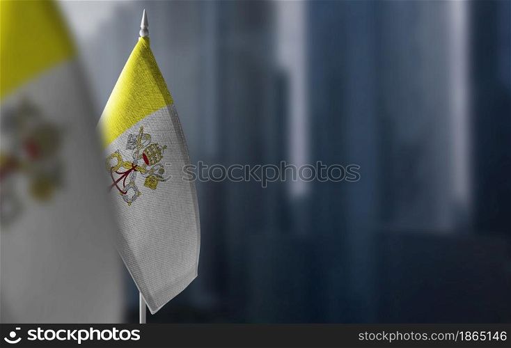 Small flags of Vatican on a blurry background of the city.. Small flags of Vatican on a blurry background of the city