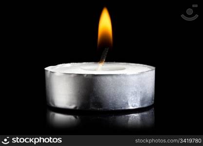 Small flame of a burning candle in darkness