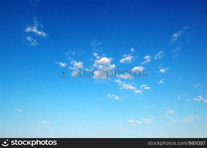 Small fluffy clouds on bright blue sky background
