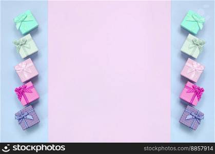 Small gift boxes of different colors with ribbons lies on a violet and pink color background.. Small gift boxes of different colors with ribbons lies on a violet and pink background