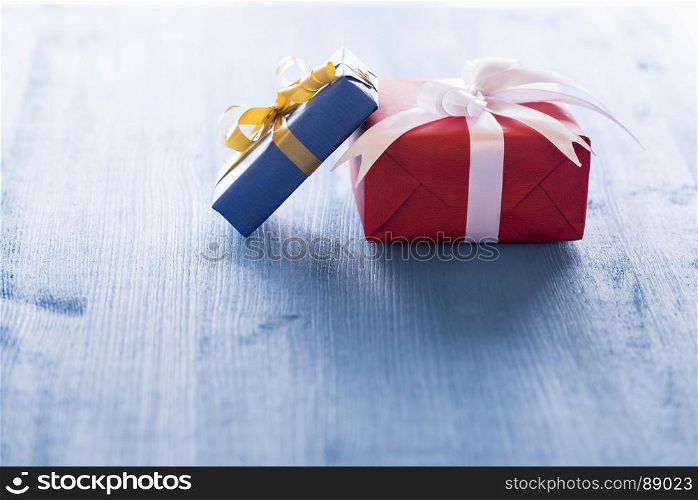 Small gift boxes with tied bow placed in sunlight on a blue wooden table