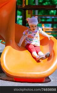 Small girl at the playground having fun on a slide