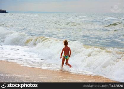 Small girl play on beach with surf