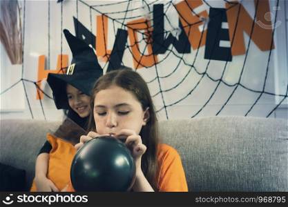 Small girl prepare decoration toy balloon for Halloween day coming soon in living room at home together