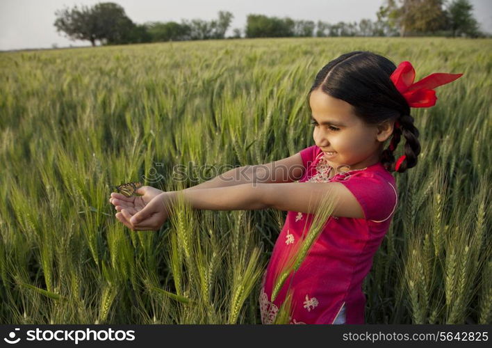 Small girl with hands cupped standing in wheat field