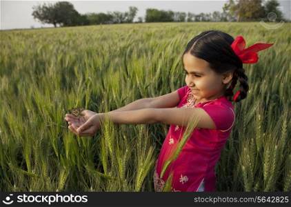 Small girl with hands cupped standing in wheat field