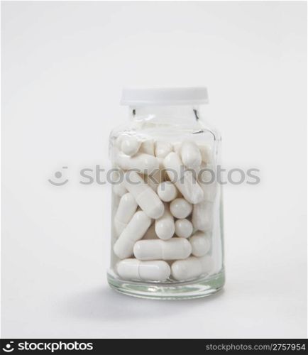 small glass botlle with medical pills, on white background