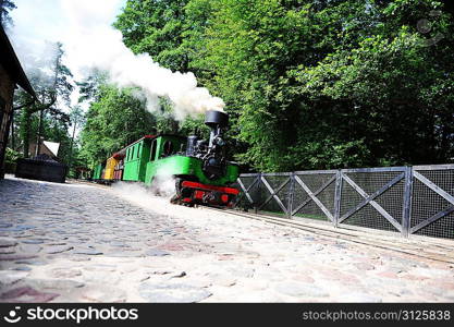small green old steam locomotive rides on rails