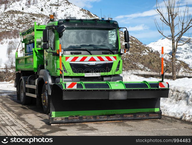 small green truck using snow plow