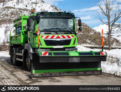 small green truck using snow plow
