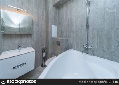 Small grey tile bathroom with bath tube and sink. Small grey bathroom