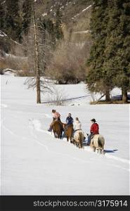Small group of people horseback riding in snow covered landscape in Colorado, USA.