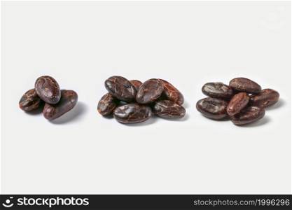 Small heaps of peeled natural beans of Theobroma cacao tree composed in row on white background. Few piles of raw organic cacao beans