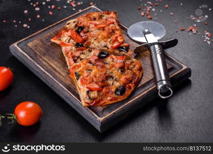 Small homemade vegetable pizza with addition of tomatoes, olives and herbs on a dark conkrete table. Homemade vegetable pizza with addition of tomatoes, olives and herbs