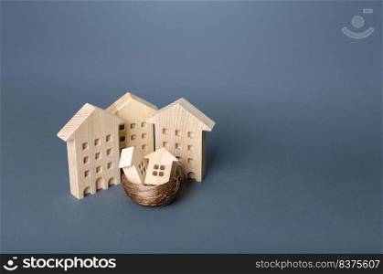 Small houses in a birds nest are surrounded by large buildings. Residential buildings and houses in a bird’s nest. Parenting metaphor. Buying a home for young families. Support in purchase of housing.