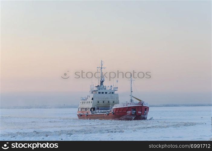 Small icebreaker among the ice on the Northern Dvina river in Arkhangelsk, North Russia. Winter frosty day.