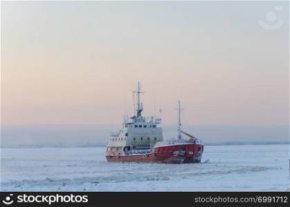 Small icebreaker among the ice on the Northern Dvina river in Arkhangelsk, North Russia. Winter frosty day.