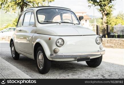 Small italian vintage car. White car.