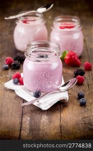 Small jars on wooden table with homemade yogurt with fresh berries