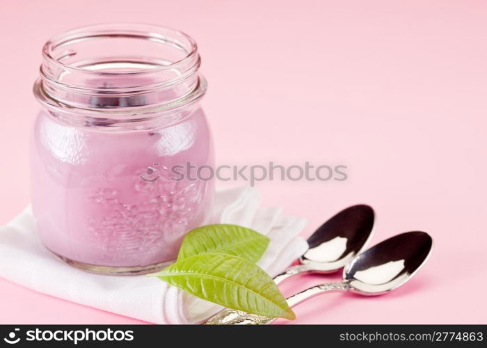 small jars with yogurt on rose background with leaves