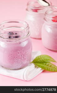 small jars with yogurt on rose background with leaves