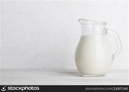 Small jug of milk on white wooden table with copy space