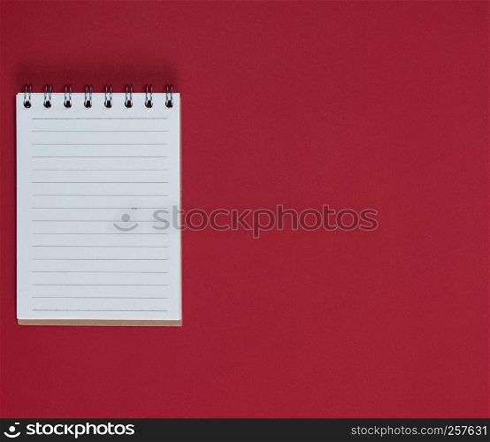 small notebook with empty white sheets in line, red background, empty space