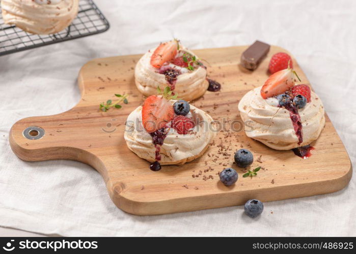 Small pavlova cakes with fresh raspberries and blueberries.