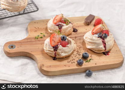 Small pavlova cakes with fresh raspberries and blueberries.