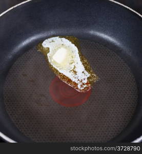 small piece dairy butter melting on hot frying pan close up