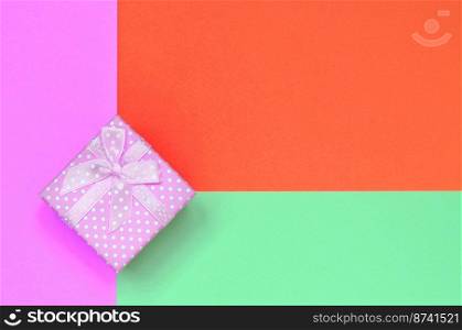 Small pink gift box lie on texture background of fashion pastel turquoise, red and pink colors paper in minimal concept.. Small pink gift box lie on texture background of fashion pastel turquoise, red and pink colors paper