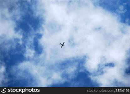 Small propeller plane flying through soft clouds and blue sky. Clouds and plane