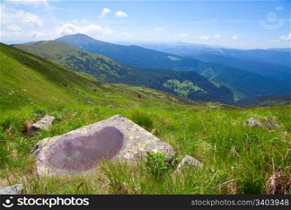 Small puddle on mountain stone with view to summer mountain landscape and cloud reflection (Ukraine, Carpathian Mountains)