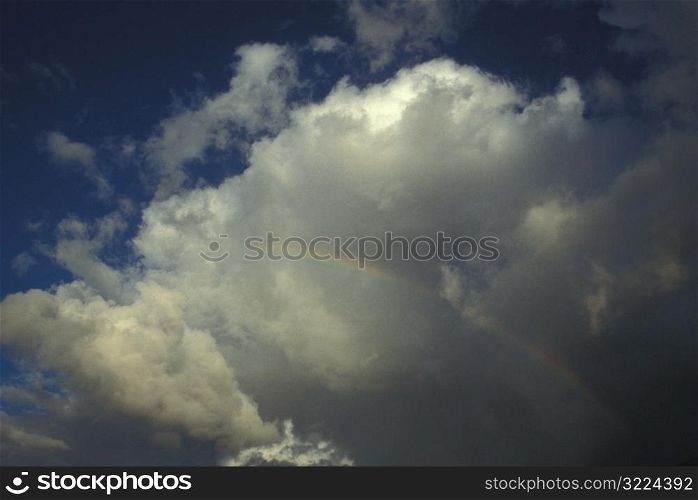 Small Rainbow In A Cloudy Blue Sky