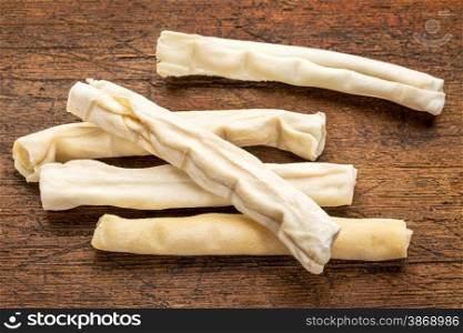 small rawhide bones - dog treats on grunge wood background