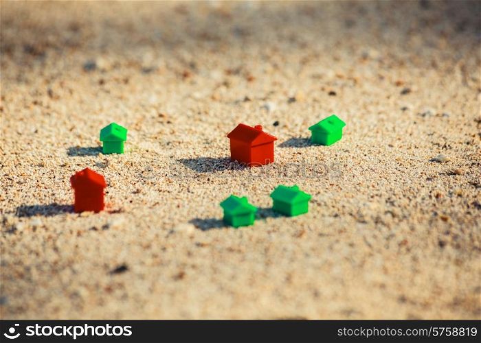 Small red and green plastic houses in the sand on the beach